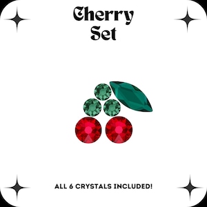 Puede incluir: Un conjunto de seis cristales de imitación rojos y verdes en forma de cerezas. El texto "Cherry Set" y "ALL 6 CRYSTALS INCLUDED!" está impreso debajo de la imagen.