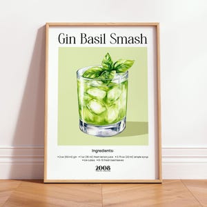 Peut inclure: Une affiche encadrée représentant une illustration de cocktail Gin Basil Smash. Le verre contient des glaçons et des feuilles de basilic. Le texte "Gin Basil Smash" est en haut, avec les ingrédients en dessous. Le cadre est de couleur marron clair.