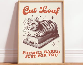 May include: A framed print with a vintage design. The print features a tabby cat shaped like a loaf of bread, resting on a wooden cutting board. The text "Cat Loaf" and "Freshly Baked Just For You" are in orange.