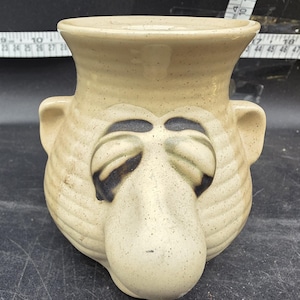 May include: A set of three ceramic mugs with a speckled, matte finish. The mugs are in shades of cream, light gray, and dark gray. Each mug has a simple, minimalist design, perfect for coffee or tea.