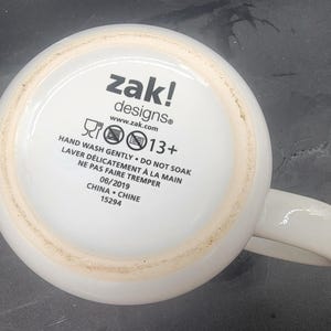Puede incluir: Taza de cer&aacute;mica blanca con un logotipo negro de zak! designs e instrucciones para lavar a mano. La taza tiene una recomendaci&oacute;n de edad de 13+ y est&aacute; hecha en China.