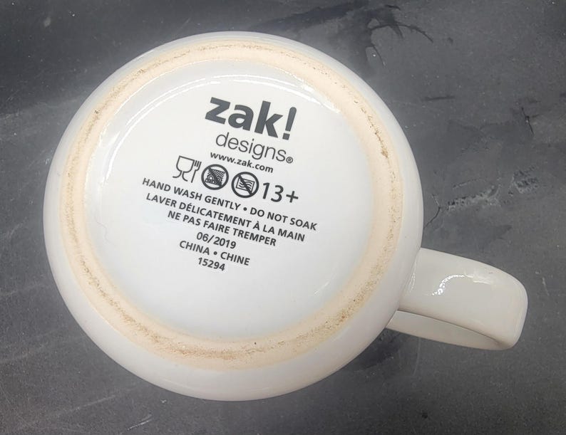 Puede incluir: Taza de cer&aacute;mica blanca con un logotipo negro de zak! designs e instrucciones para lavar a mano. La taza tiene una recomendaci&oacute;n de edad de 13+ y est&aacute; hecha en China.