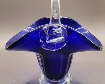 Peut inclure: Un panier en verre bleu cobalt avec une poignée en verre transparent. Le panier a un design cannelé et une base en verre transparent.