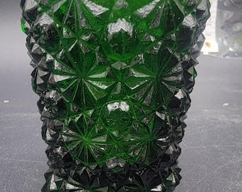 May include: A green glass vase with a diamond pattern. The vase has a wide mouth and a rounded base.