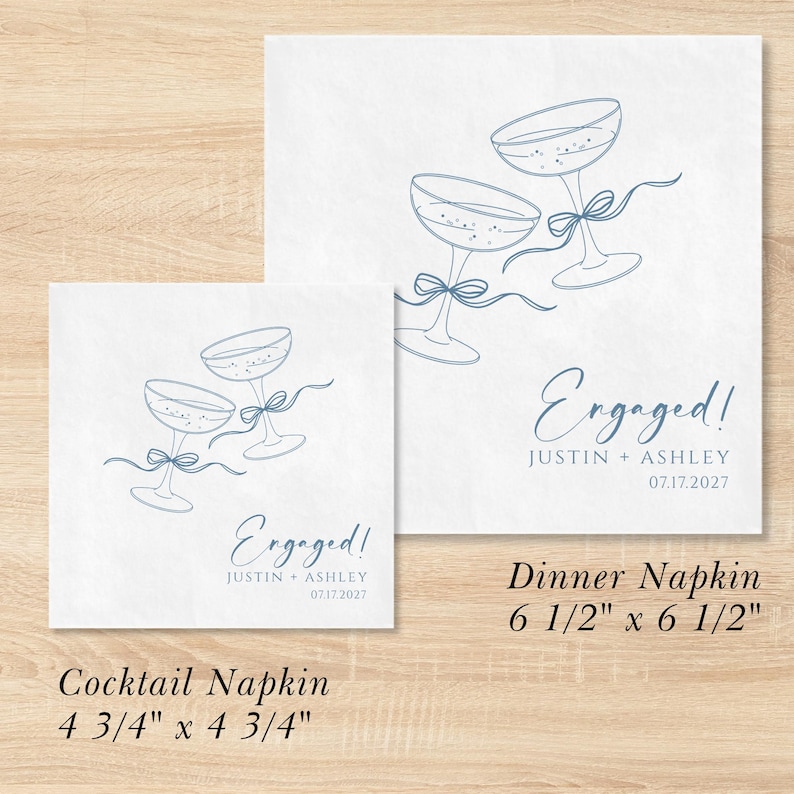 May include: Two white square paper napkins featuring blue line art of two champagne glasses tied with a ribbon. The text reads Engaged! Justin + Ashley 07.17.2027. The cocktail napkin measures 12.07 cm by 12.07 cm and the dinner napkin 16.51 cm by 16.51 cm.
