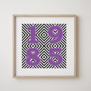 Può includere: Una stampa incorniciata con un motivo geometrico bianco e nero che presenta il numero 1985 in viola.