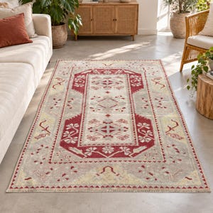 May include: A rectangular area rug featuring a central medallion design with a cream-colored background, accented by deep red borders and soft yellow geometric floral motifs, finished with a short fringe along the narrow edges.