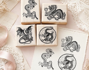 May include: Four square wooden rubber stamps featuring detailed black ink illustrations of dragons. The designs include a long serpentine dragon, a dragon holding a sphere, a winged dragon, and a dragon coiled within a circular cloud pattern.