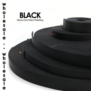 May include: Black heavy-duty nylon webbing rolls. The image shows several rolls of black nylon webbing, with the word "BLACK" and "Heavy Duty Nylon Webbing" in white text. Pins are inserted into the webbing.