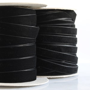May include: Two spools of black velvet ribbon, wound tightly on cardboard spools.