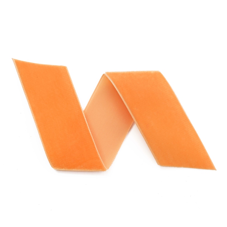 K&ouml;nnte beinhalten: Ein leuchtend orangefarbenes Samtband ist zu einer dekorativen Form gedreht und gefaltet.