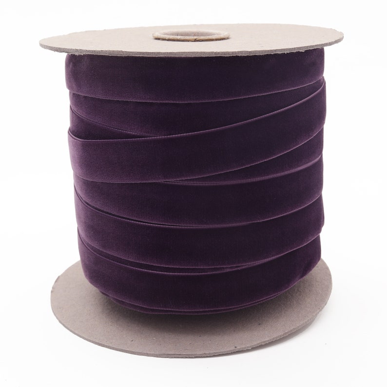 Peut inclure: Une bobine de ruban de velours violet enroul&eacute; autour d'un noyau en carton. Le ruban mesure environ 2,5 cm de large.