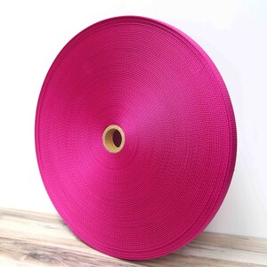 May include: A roll of bright pink nylon webbing, a type of strong, durable fabric often used for straps, belts, and other applications.