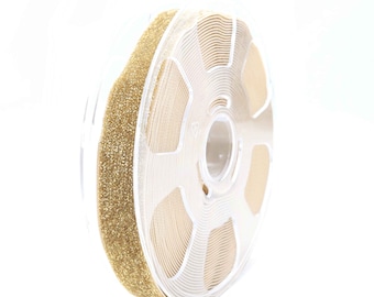 May include: A spool of gold glitter ribbon with a clear plastic dispenser. The ribbon is wound around the dispenser and is ready to be used for crafting or decorating.