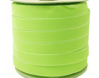 May include: A spool of bright green velvet ribbon. The ribbon is wound around a cardboard spool.