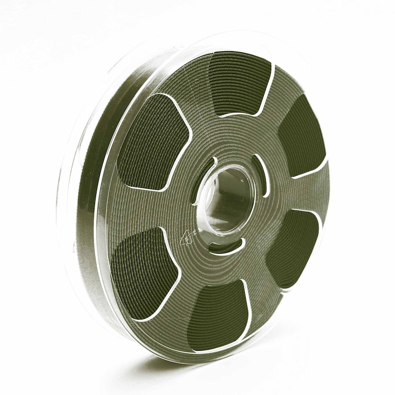 May include: A black and silver film reel with a clear plastic case. The reel is full of film and has a series of concentric circles.