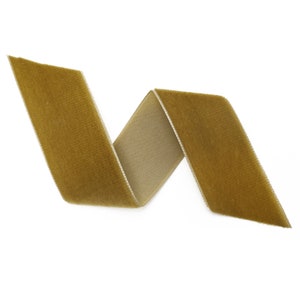 May include: A gold velvet ribbon with a slight sheen, folded in a simple, elegant curve.