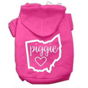 Puede incluir: Sudadera rosa para perro con un contorno blanco del estado de Ohio y la palabra "piggie" en su interior. Un peque&ntilde;o coraz&oacute;n blanco est&aacute; dentro del contorno.