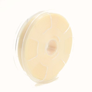 Peut inclure: Une bobine de ruban en tissu blanc cassé enroulée autour d'une bobine en plastique transparente.