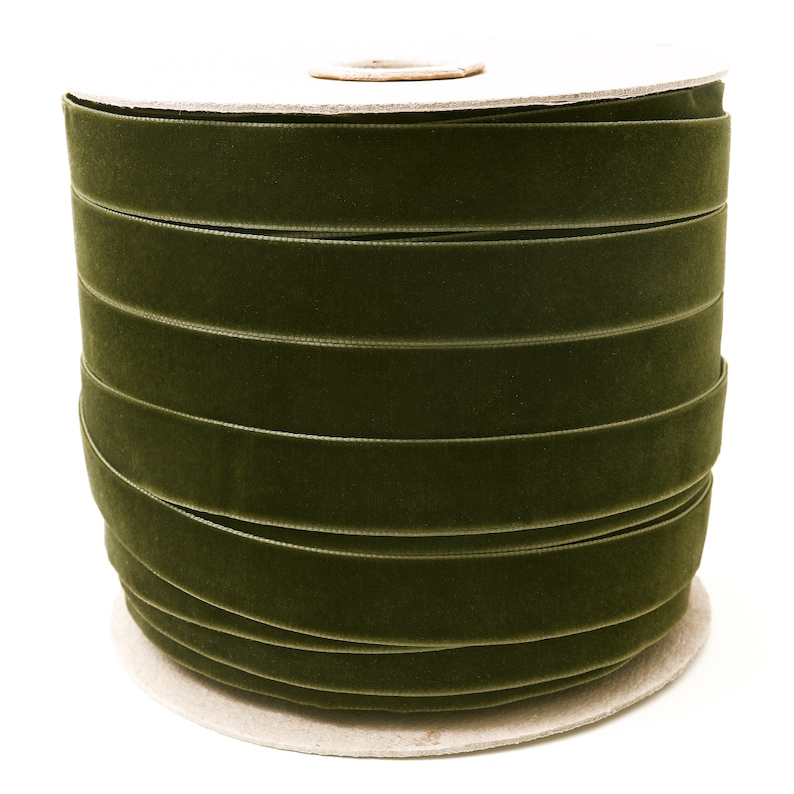 May include: A spool of dark green velvet ribbon. The ribbon is wound tightly around a cardboard spool.