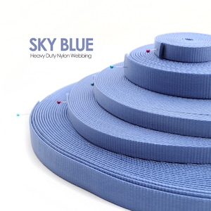 May include: Sky blue heavy duty nylon webbing in various widths. The webbing is rolled up in a stack, with each roll secured with a pin.