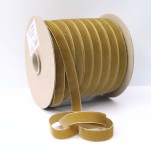 May include: A spool of gold velvet ribbon. The ribbon is approximately 1/2 inch wide and is wound around a cardboard spool.