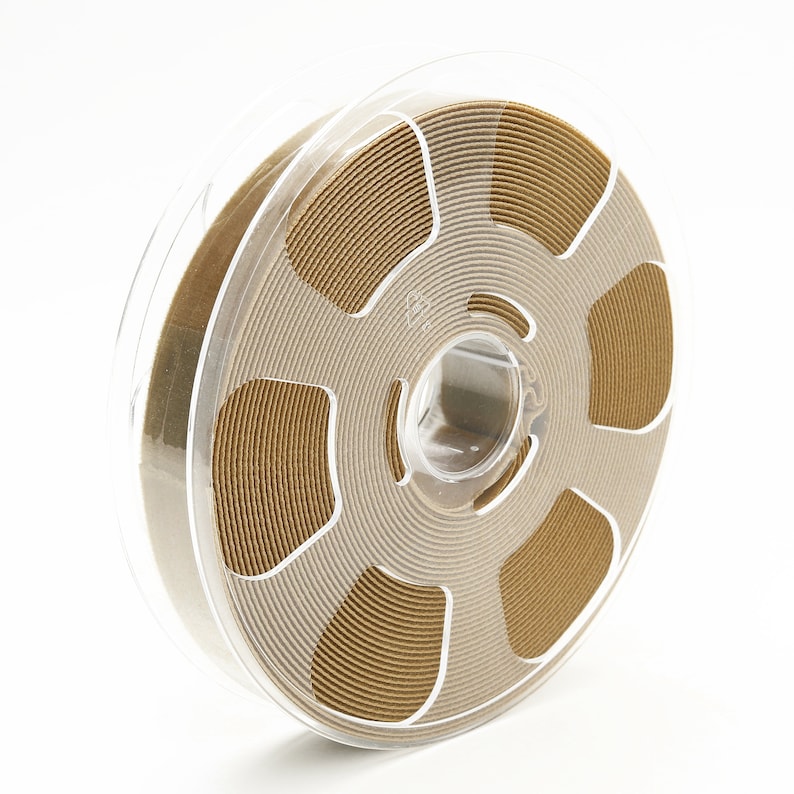May include: A spool of gold-colored ribbon wound around a clear plastic bobbin. The ribbon is wound in concentric circles, creating a decorative pattern.