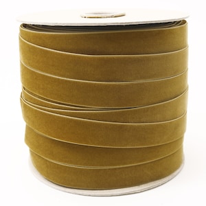 May include: A spool of gold velvet ribbon. The ribbon is wound tightly around the spool, creating a smooth, even surface.