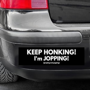 May include: A black bumper sticker with white text that reads "KEEP HONKING! I'M JOPPING! (jumping and popping)"