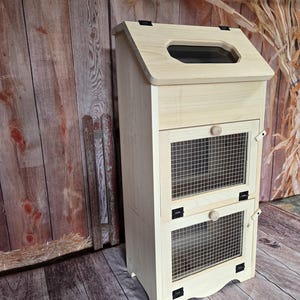 May include: A wooden cabinet with two wire mesh doors and a hinged top with a small window. The cabinet is painted white and has black hinges.