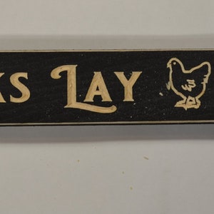 May include: Black wooden sign with the text "Wicked Chicks Lay Deviled Eggs" in gold lettering. A stylized chicken silhouette is between the words "Lay" and "Deviled".