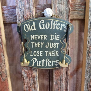 Painted shaped wooden &quot;Golfers Never Die They Just Lose Their Putters&quot; sign with two 3D Putters and Golf Ball On the top Hanging Wire