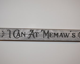 May include: A rustic wooden sign with the text "I Can At Memaw's" in black lettering.