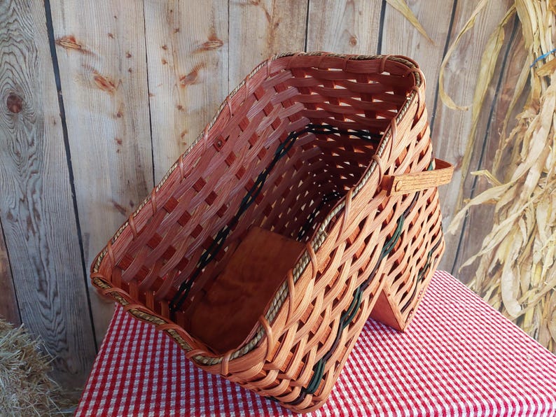 May include: A large, woven basket with a brown and green pattern. The basket has a handle and is made of natural materials.