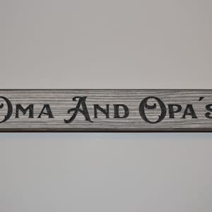 May include: A rustic wooden sign with the text "OMA AND OPA'S" in black lettering.