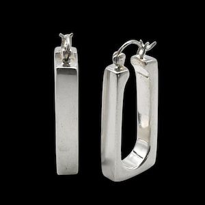 May include: A pair of rectangular hoop earrings crafted from polished silver. Each earring features a smooth, elongated, four-sided frame with a hinged post mechanism at the top, showcasing a clean, metallic finish and a structured, geometric design.