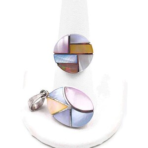 May include: A set of two jewelry pieces featuring a round pendant and a matching oval pendant. Both pendants are made of silver and have a geometric design with inlaid pieces of iridescent mother-of-pearl in shades of pink, blue, yellow, and brown.