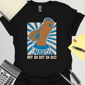 May include: Black t-shirt featuring a cartoon donkey illustration with the text "NARD RIT DI DIT DI DO" in a blue and white design. The donkey is brown with blue accents, set against a blue and white striped background.