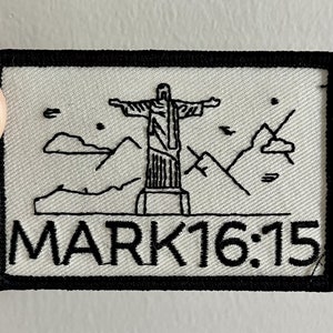 May include: Black and white embroidered patch featuring a silhouette of Jesus Christ with outstretched arms, standing on a pedestal with mountains in the background. The text "MARK 16:15" is embroidered below the image.