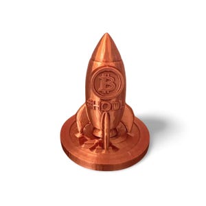 May include: A copper-coloured rocket ship figurine featuring the Bitcoin symbol and the word "HODL". The rocket sits on a round base. This decorative item is a collectible.