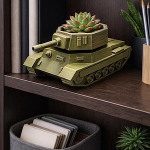 May include: A decorative olive green tank-shaped planter with a succulent plant. The planter sits on a dark brown shelf, with books and other decor in the background. The tank planter is approximately 8 inches long.