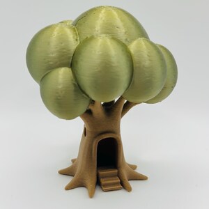 May include: A 3D-printed miniature tree with a whimsical design. The tree features a brown trunk with a doorway and steps, and a cluster of olive-green, spherical leaves. The overall aesthetic is reminiscent of a fairy tale or fantasy setting.
