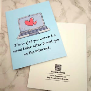 May include: A light blue greeting card with a cartoon illustration of a laptop with two hearts on the screen. The text on the card reads "I'm so glad you weren't a serial killer after I met you on the internet."