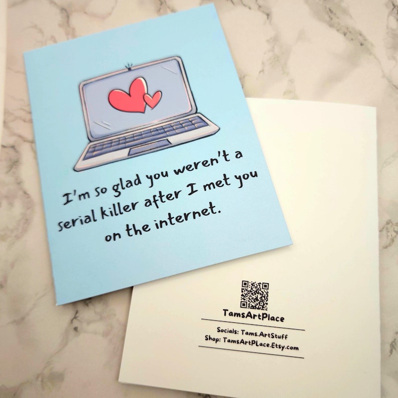 May include: A light blue greeting card with a cartoon illustration of a laptop with two hearts on the screen. The text on the card reads "I'm so glad you weren't a serial killer after I met you on the internet."