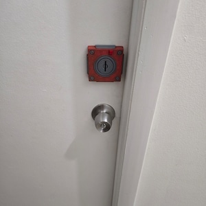 May include: A red and gray door lock with a keyhole and a silver door knob.