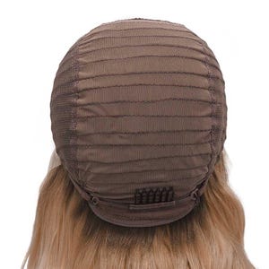 May include: A brown wig cap with a mesh construction and horizontal stitching. The cap features a series of small clips at the nape of the neck. Blonde hair is visible beneath the cap.
