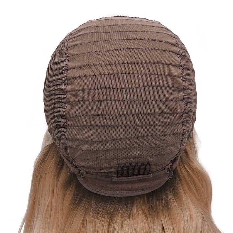 May include: A brown wig cap with a mesh construction and horizontal stitching. The cap features a series of small clips at the nape of the neck. Blonde hair is visible beneath the cap.