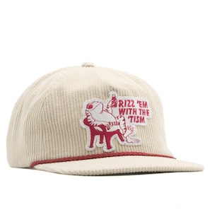 May include: A cream-colored corduroy baseball cap featuring a red embroidered patch of a frog sitting in a chair holding a bottle. The patch includes the red text RIZZ 'EM WITH THE 'TISM. A thin red rope trim runs across the base of the crown.