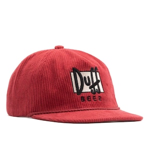 Puede incluir: Gorra de béisbol de pana roja con visera curva. La gorra presenta el texto "Duff Beer" en un diseño en blanco y negro en la parte delantera. La gorra tiene una corona estructurada y un cordón en la visera.