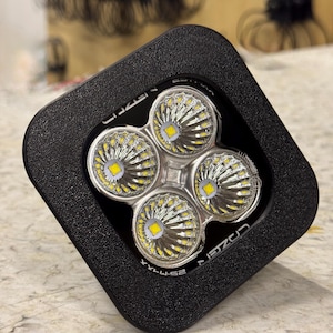 May include: A black square-shaped LED light with four round LED bulbs. The light has the text "CREE" printed on the side.